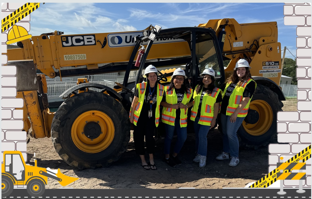 Picture of teachers in a construction site holding shovels in front of heavy-duty construction equipment.